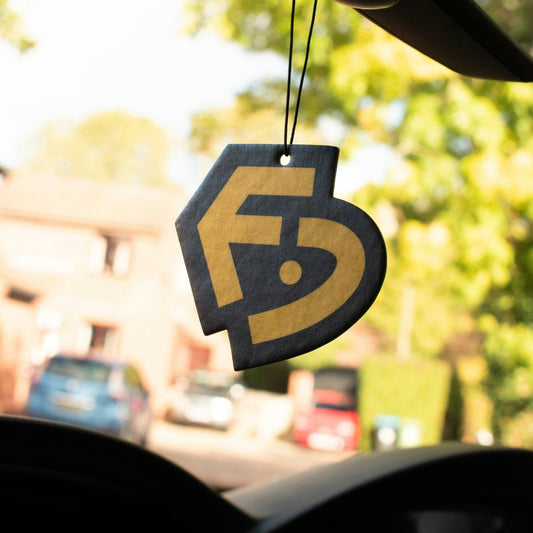Factory Delete car air freshener in the shape of the FD logo hanging from a rear view mirror
